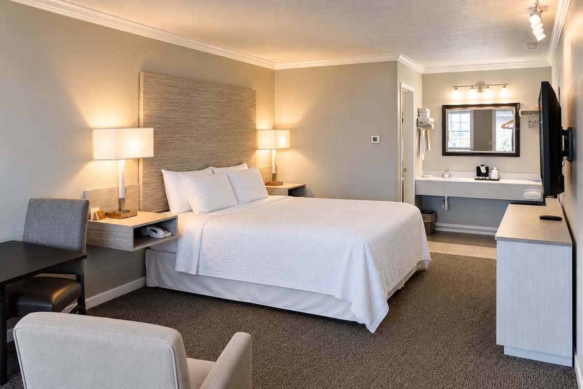 King bed with white bedding, table and chairs in the King Room